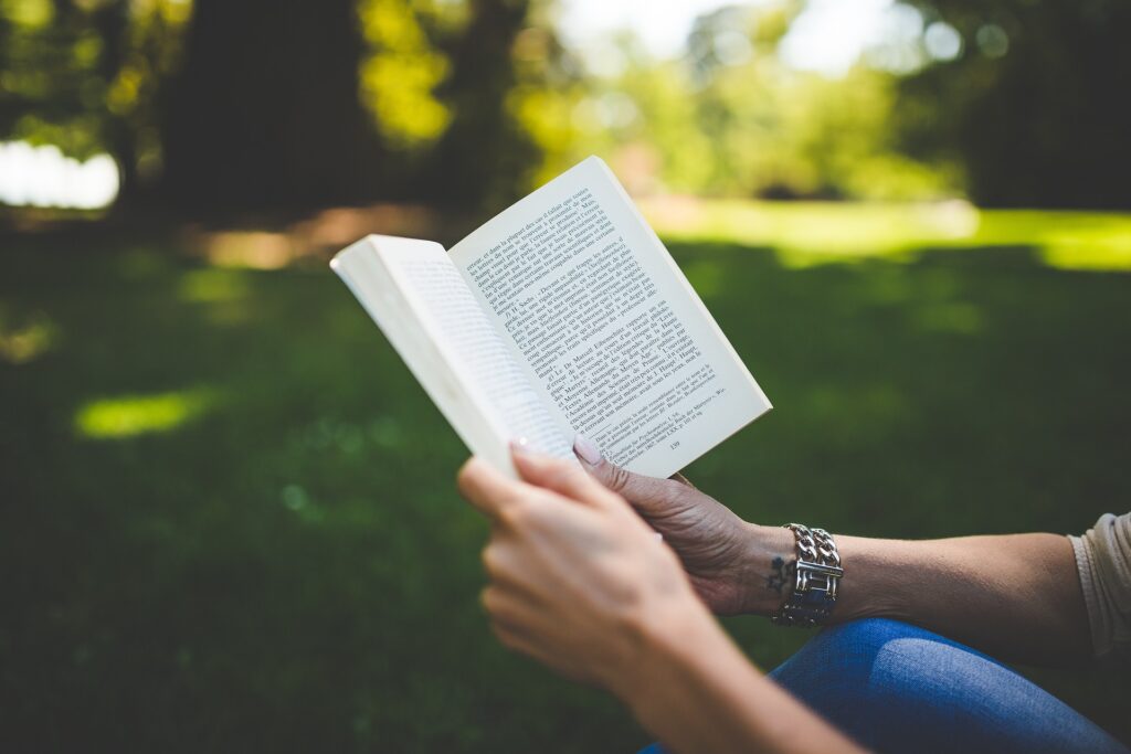 Kvinna läser bok i skogsdunge